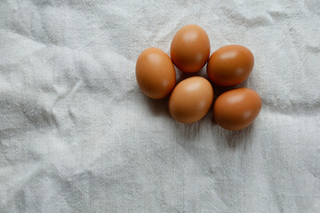 A group of five brown eggs arranged on a textured white cloth.