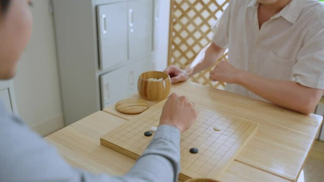 Close up of young men play board game Go during competition in community. 