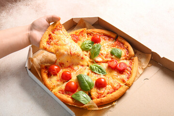 Woman taking slice of tasty pizza margarita on white table