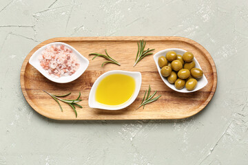 Bowls with ripe olives, salt and oil on light background