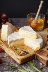 Wooden board with tasty Camembert cheese on table