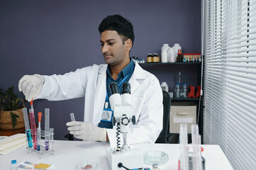 Scientist wearing lab coat and gloves conducting experiment in laboratory with various scientific...