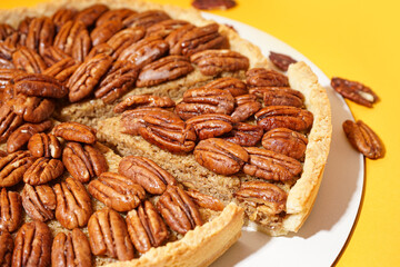 Tasty pecan pie on yellow background