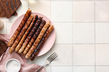 Plate of tasty grilled sausages on white tile background