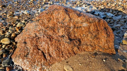 Large Reddish Rock on a Sandy Beach