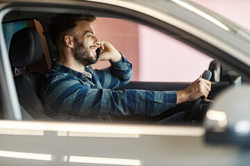 Side view of car driver driving his car and having phone conversation.