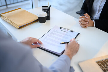 Close up of HR recruiter reviewing a candidate resume during a job interview