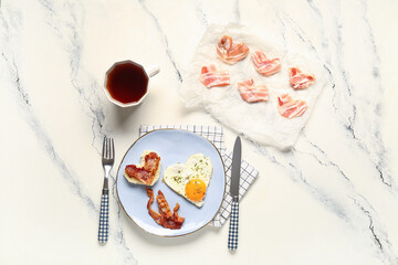 Composition with tasty bacon, fried egg and cup of tea on light background