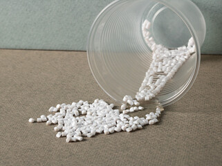Plastic granules spill out of a cup. Microplastics in the environment.