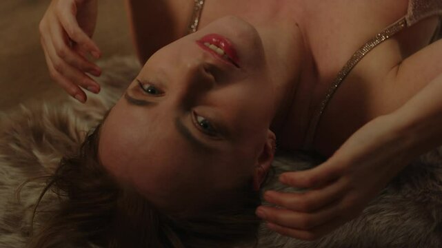 Portrait of an attractive woman lying on a rug sensually caressing her face and moaning in pleasure