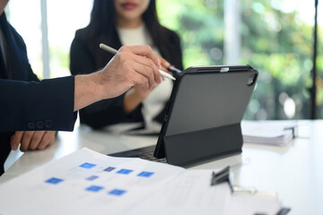 Close up of professionals business people analyzing charts and graphs on digital tablet at office