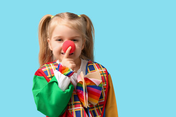 Funny little girl in clown costume on blue background