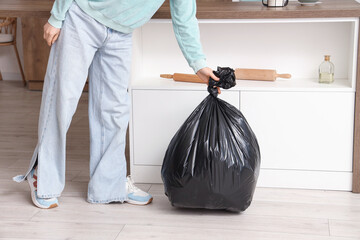 Woman with full garbage bag in kitchen