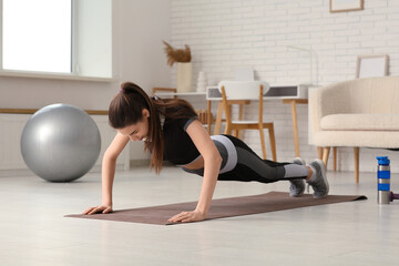 Beautiful young sporty woman doing pushups at home