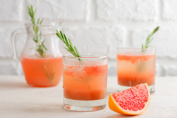 Cold grapefruit and peach drink, tea, lemonade, cocktail with rosemary in glasses and jar and a...