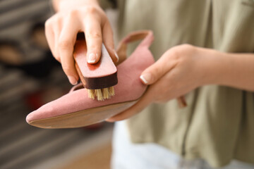 Woman cleaning suede shoe with brush, closeup