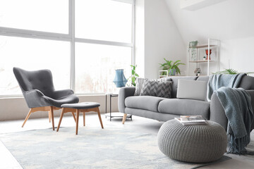 Stylish interior of white living room with black sofa and armchair