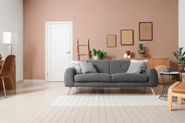 Stylish interior of beige living room with cozy sofa and armchair