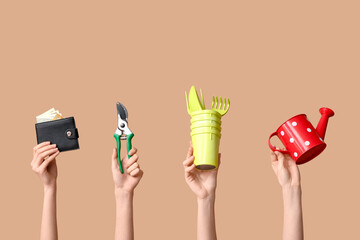 Female hands with gardening tools and wallet on color background