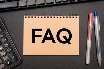 FAQ text on Notebook with calculator and office supplies. FAQ frequently asked questions.