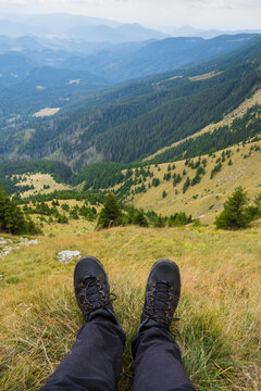 A Scenic View Of Rolling Hills And Dense Forests Captured From The Perspective Of Someone Relaxing With Hiking Boots In The Foreground