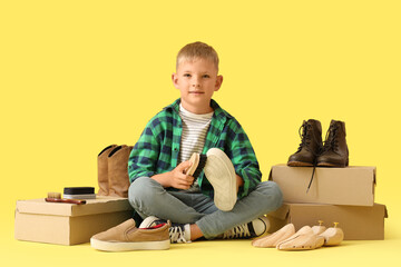 Cute little cobbler cleaning shoes on yellow background