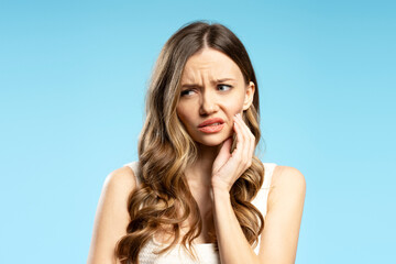 Young Woman Suffering From Toothache Touching Cheek on Blue Background