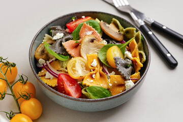 Bowl with delicious Italian pasta salad on grey background