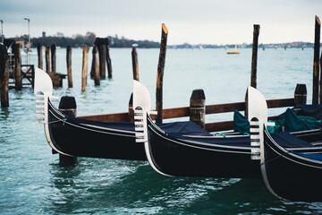 Venetian gondolas docked in calm waters on a cloudy day