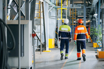 Team of Industrial Worker inspection at steel long pipes and pipe elbow in thermal power plant, back view.