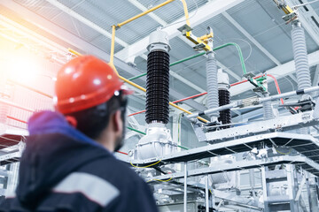 Electrical engineer worker inspects electrical substation with high voltage switches, wires,...