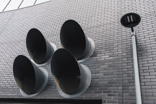 An array of unique architectural speakers adorns an urban wall, merging functionality with artistic flair and enhancing the acoustic experience for passersby.