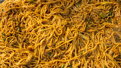 A close-up shot of stir-fried noodles or spaghetti with fresh vegetables in a rich sauce, cooked to perfection, presenting a delicious and appetizing dish for food lovers.