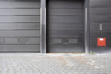 The image showcases two sleek, modern garage doors in a contemporary urban setting, emphasizing minimalism and the stark design of industrial architecture.