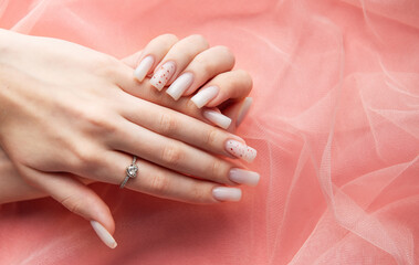 Woman showing stylish white nails and engagement ring on pink background