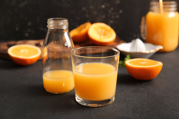 Glass and bottle of fresh orange juice on black background