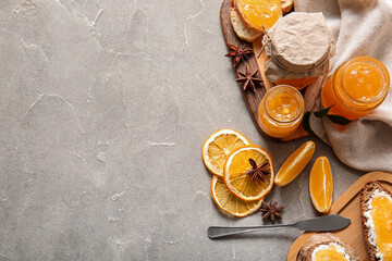 Jars of sweet orange jam with star anise and fruits on grey background