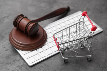 Auction gavel with shopping cart and computer keyboard on dark background, closeup