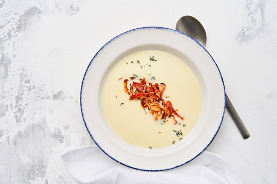A delicious creamy soup topped with vibrant garnishes sits in a white bowl. Fresh herbs and colorful ingredients enhance the dish's inviting appearance perfect for lunch