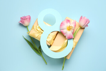 Figure 8 made of ribbon, tulip flowers and gift boxes on blue background. Women's Day celebration.