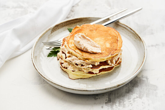 A stack of fluffy pancakes rests on a rustic plate, generously topped with a dollop of creamy frosting. This scrumptious breakfast is perfect for starting the day on a delightful note