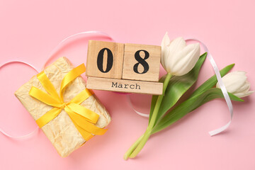 Cube calendar, flowers and gift box for International Women's Day celebration on pink background