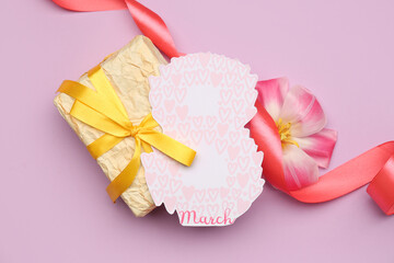 Gift box, greeting card and flower for Women's Day celebration on lilac background