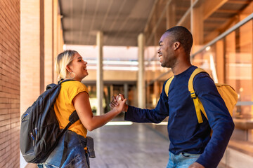 Happy multi-ethnic students shaking hands at the university
