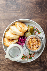 A delightful platter featuring a jar of pâté, served with toasted bread slices, pickles, and pickled onions. Garnished with colorful spices, perfect for a gourmet dining experience.