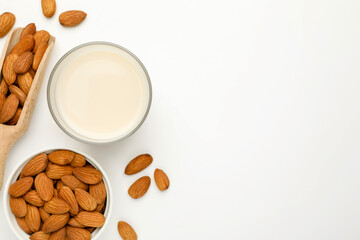 Fresh nut milk in glass and almonds on white table, flat lay. Space for text