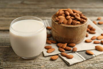 Fresh almond milk in glass and nuts on wooden table, closeup