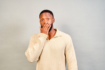 Shocked young man covering mouth with hand in studio
