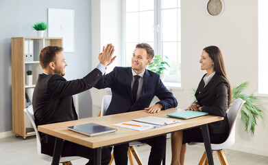 Group of young three business people sitting in office and rejoicing at the deal is struck. Company...