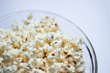 Tasty popcorn in a glass bowl on white table background 